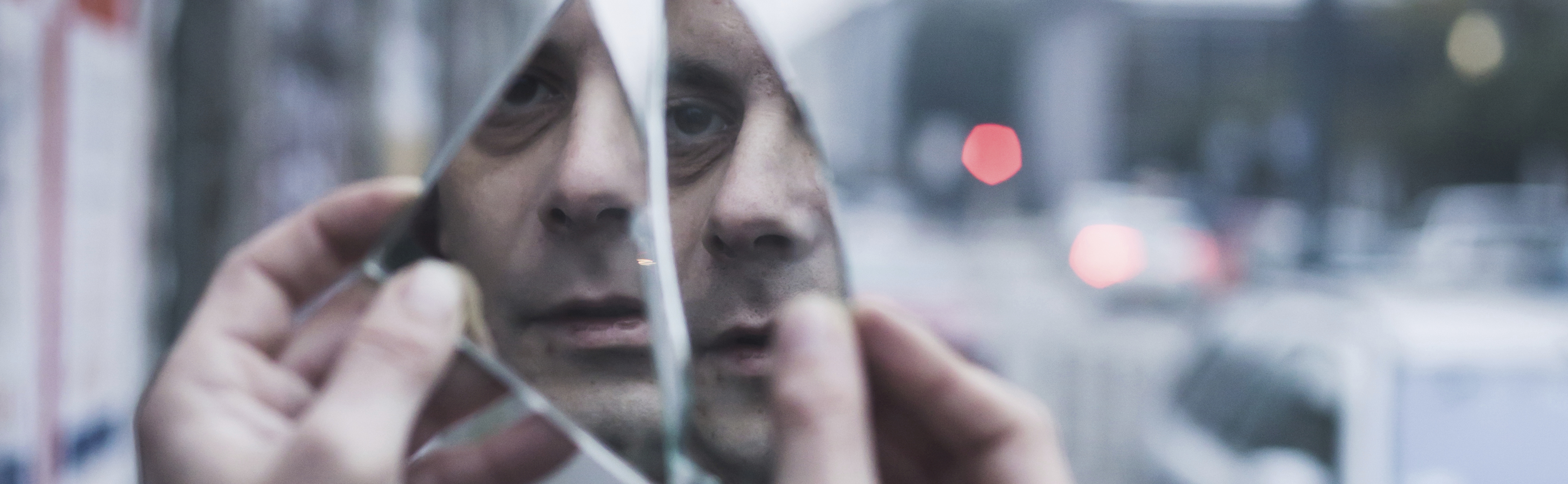 Punk guy looking at himself in a shattered mirror